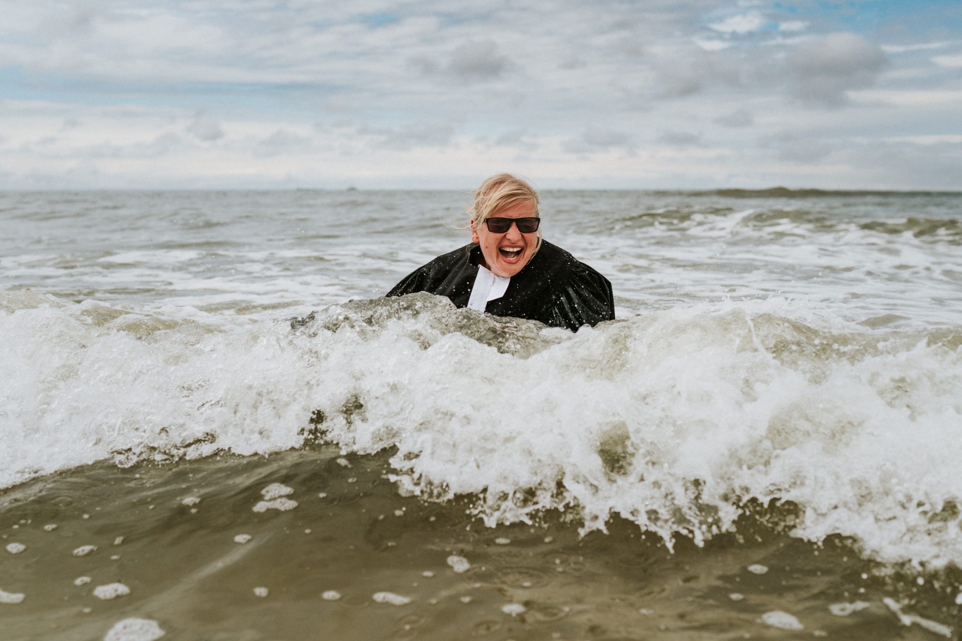 Inselpastorin Jeannette Schurig fällt während des Tauffestes am Strand von Langeoog im Talar in die Nordsee